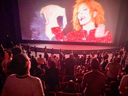 Une vue de la salle avec les spectateurs dansant sur la scène et depuis leur place
